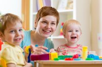 Smiling woman playing with two children in a daycare setting
